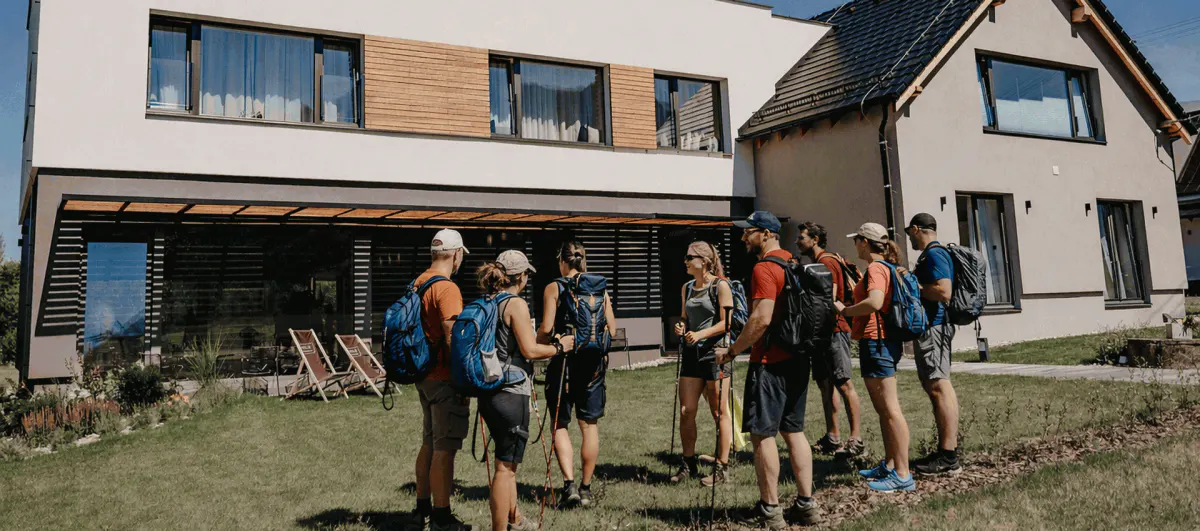 Skupina lidí s batohy před budovou hotelu Maralák za slunečného dne