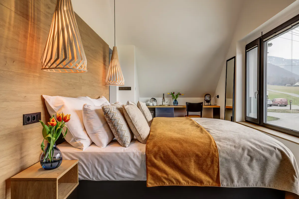 Designový hotelový pokoj s dřevěnými svítidly a výhledem na hory z okna